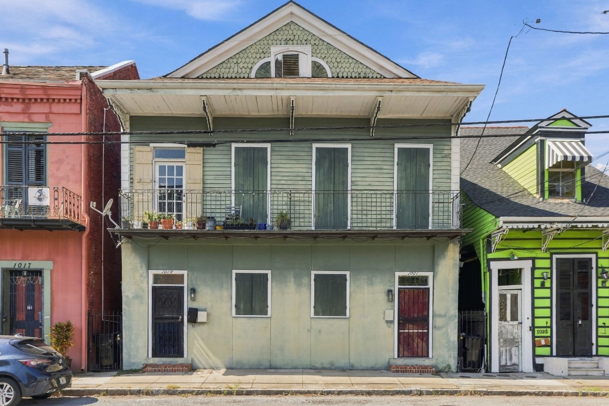 1021 Henriette Delille Street, a sage green two-story Creole townhouse with a wrought iron balcony and wood shutters in the Tremé, New Orleans