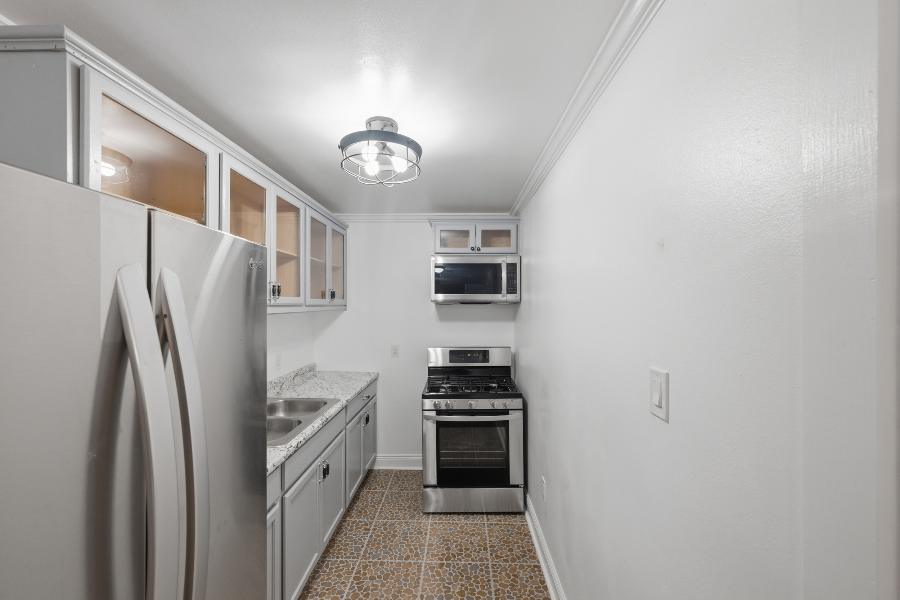 Galley kitchen with stainless refrigerator, gas range and microwave
