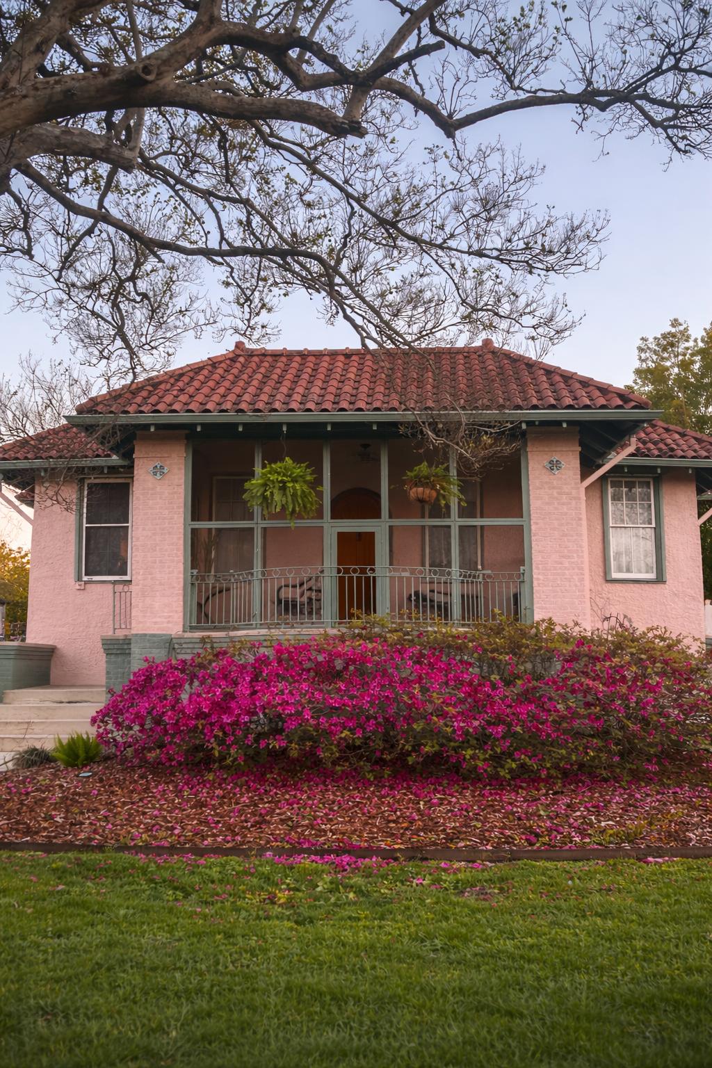 Pink stucco bungalow with a tile roof and azaleas in Broadmoor, New Orleans