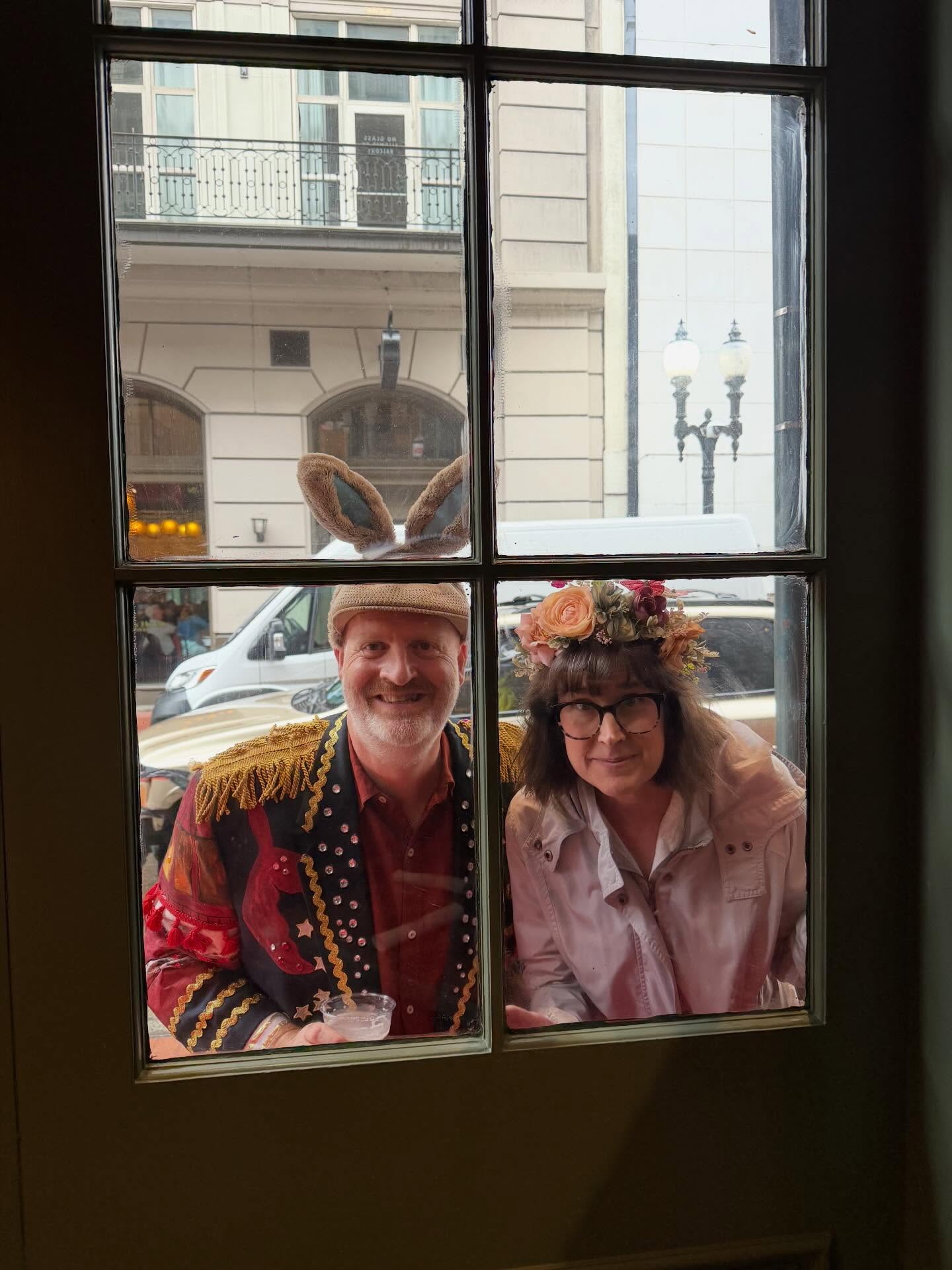 Cameron Smith and his wife in festive costume framed in a historic French Quarter window in New Orleans