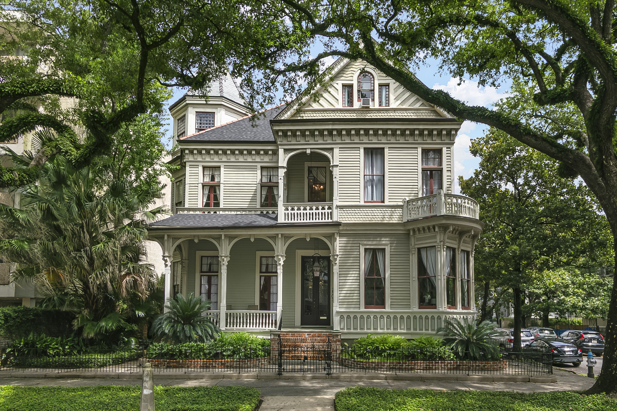 Grand sage-green Victorian mansion framed by live oaks in the Garden District of New Orleans